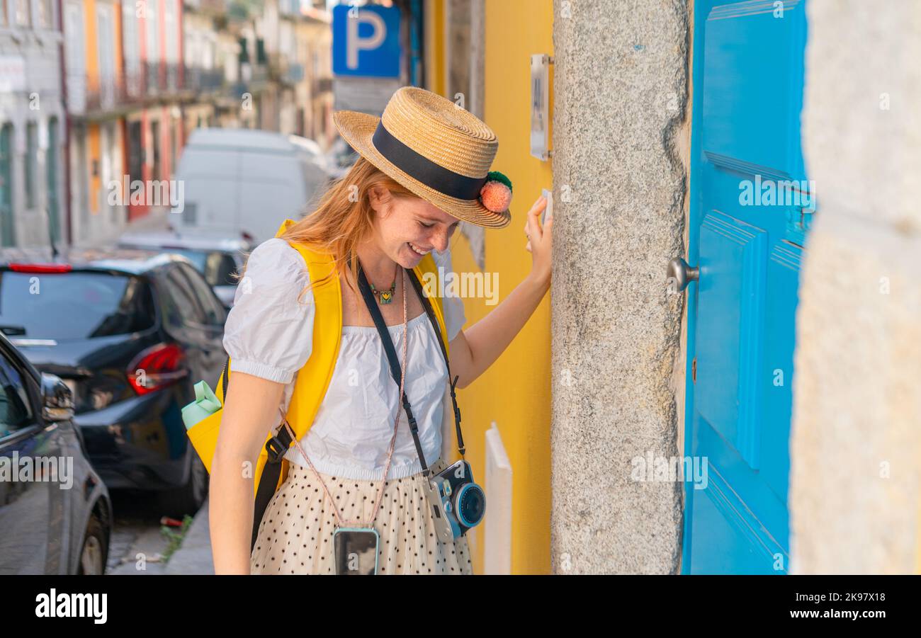 Tourist woman ringing on doorbell at the AL entrance in Portugal town Stock Photo