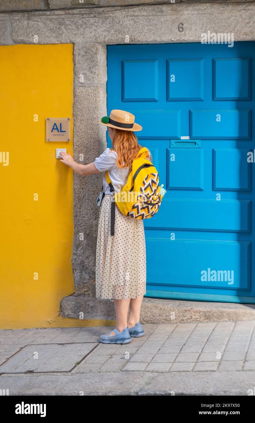 Tourist woman ringing on doorbell at the AL entrance in Portugal town Stock Photo