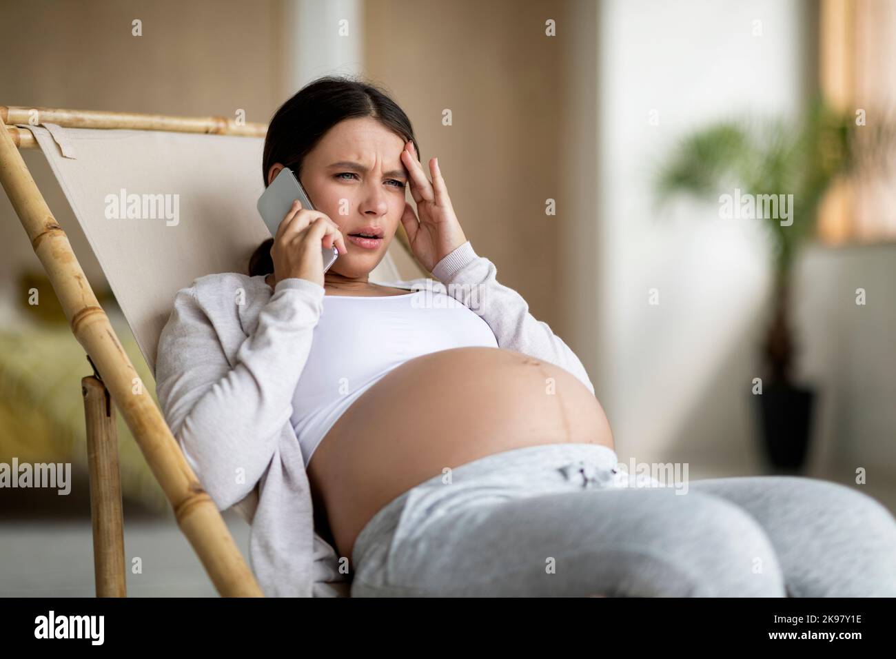 Sad pregnant woman sitting chair hi-res stock photography and