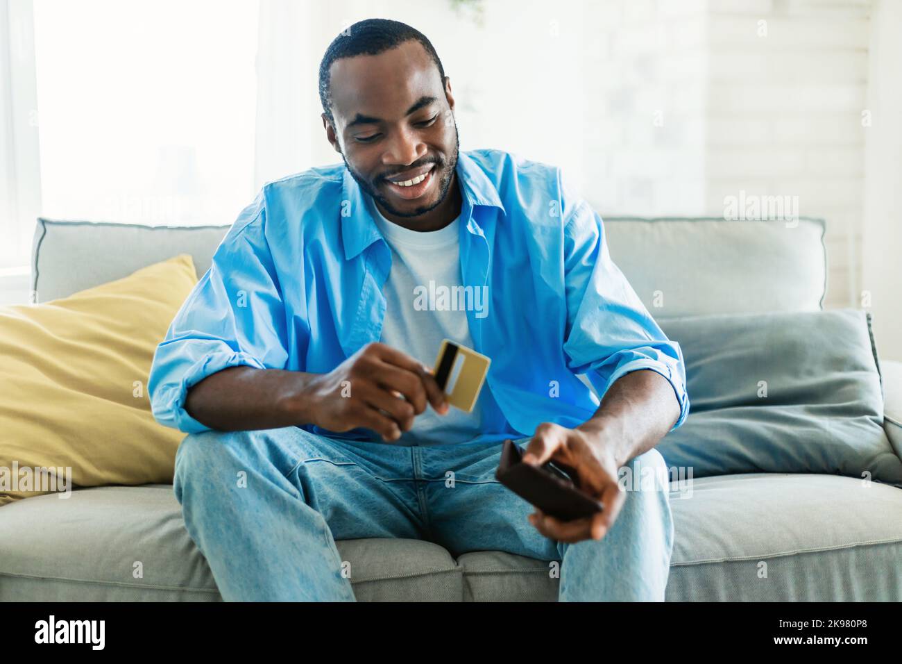 Excited african american man selecting credit card from his card wallet