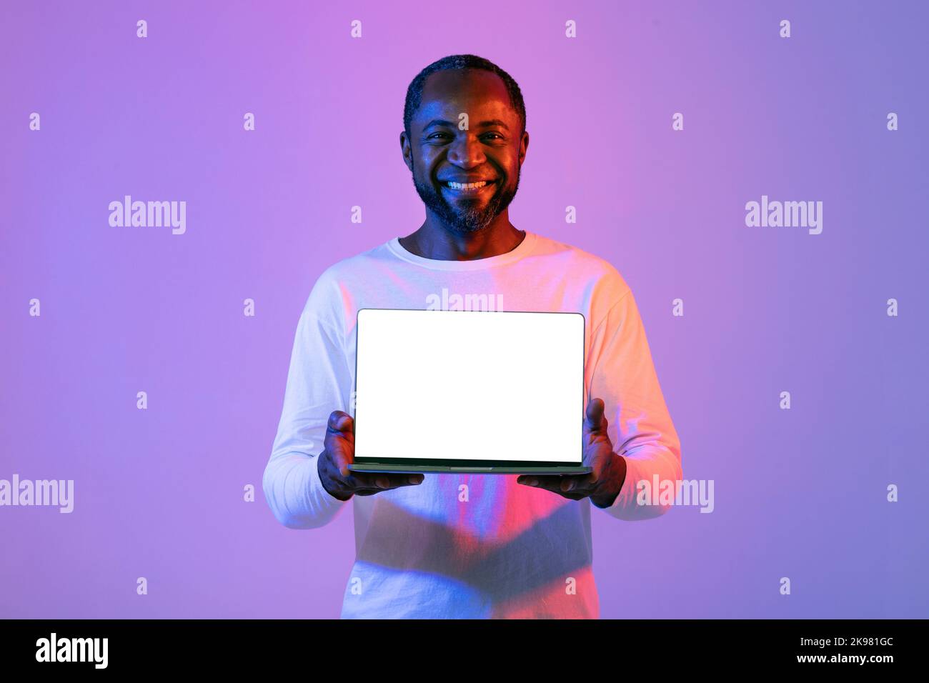 Positive african american mature man showing laptop, mockup Stock Photo ...