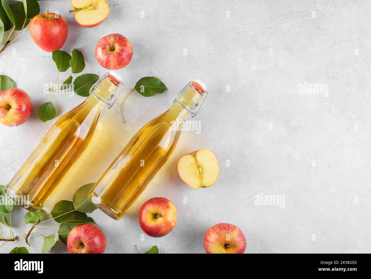 Apple cider vinegar in a two glass bottles and fresh apples with leaves ...
