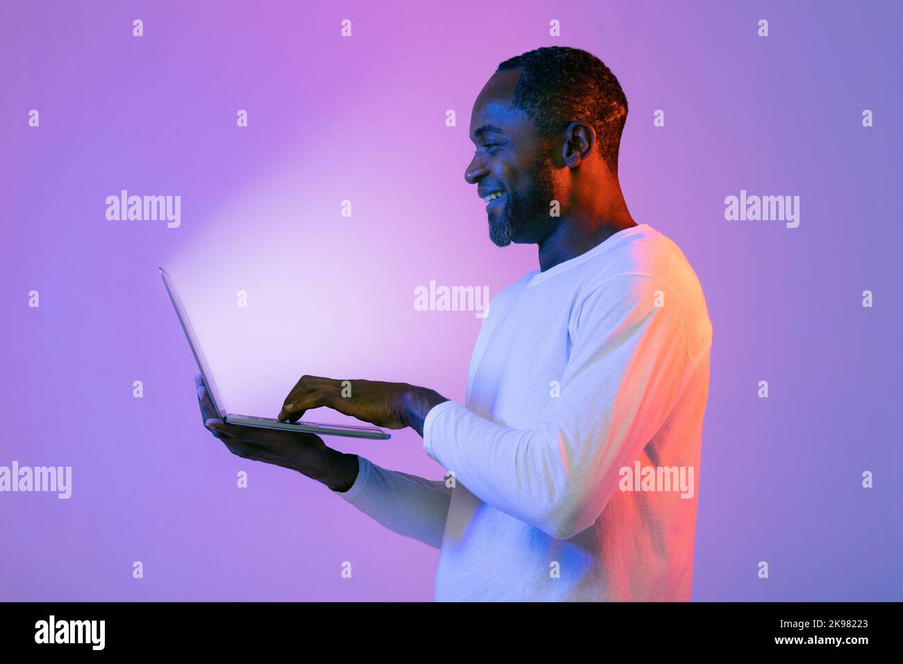 Cheerful black man using modern laptop with shining screen Stock Photo