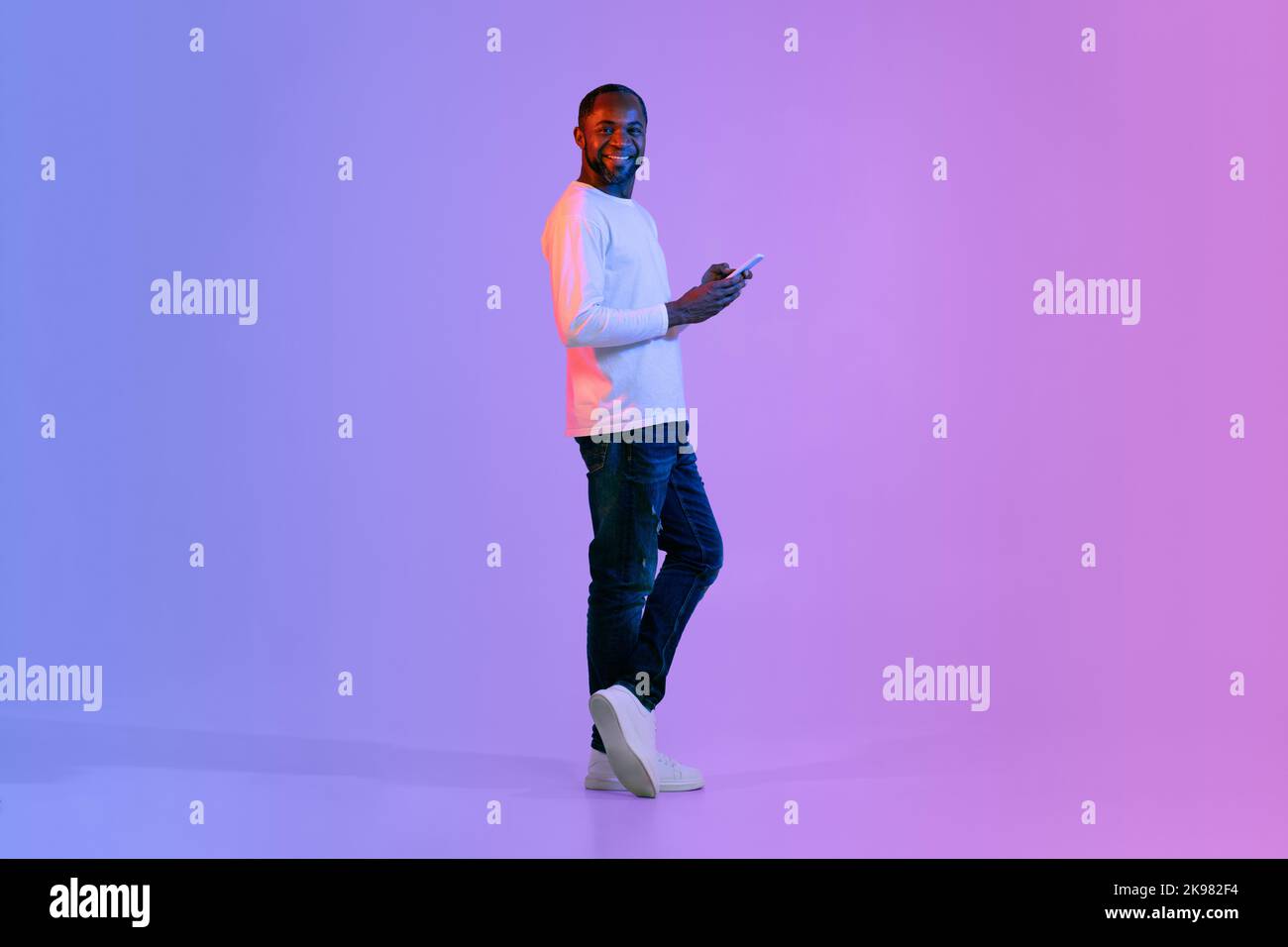 Cheerful black man using smartphone and smiling Stock Photo