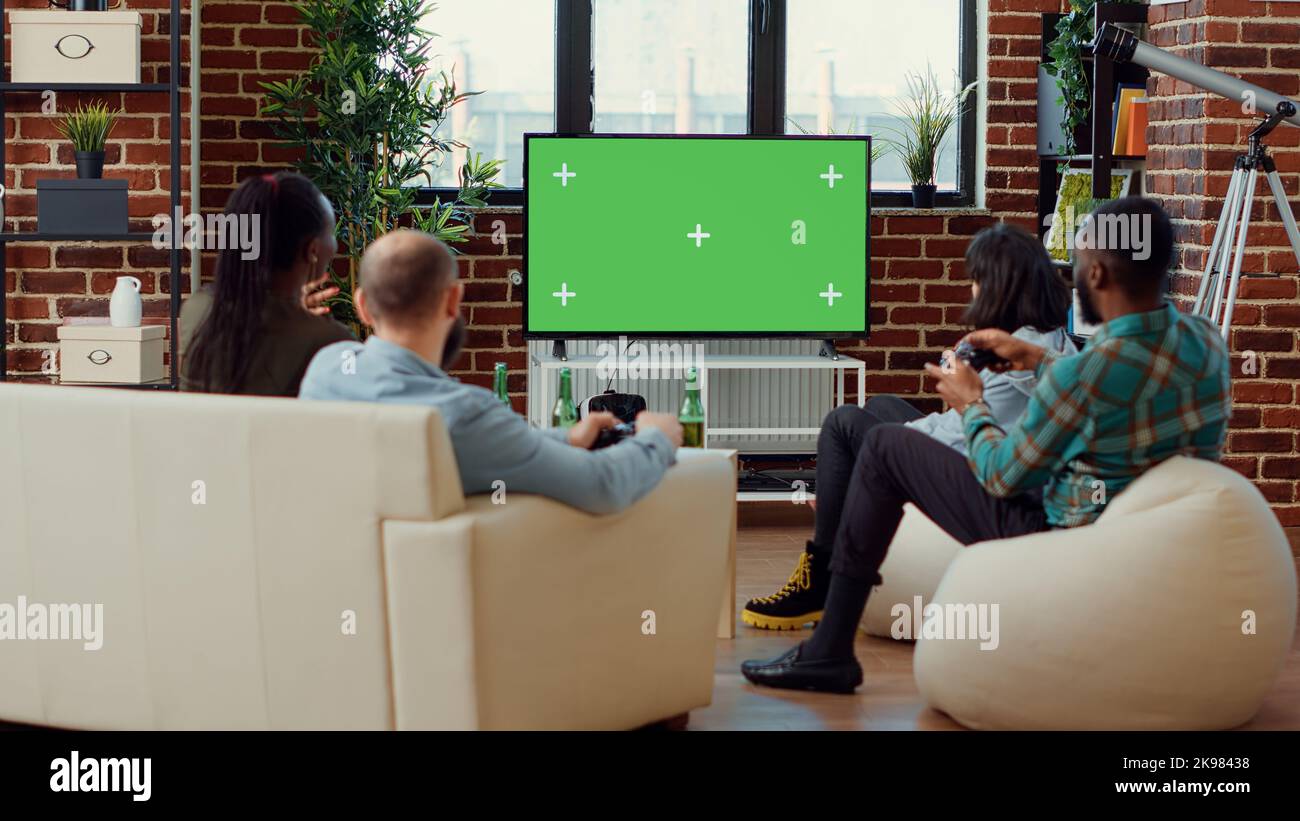 Happy friends playing video games on greenscreen background, enjoying