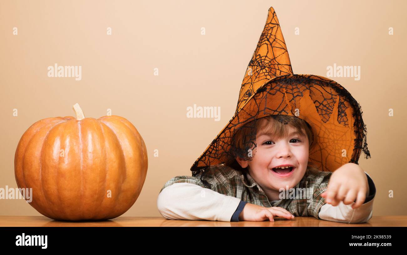 Child in witch hat with halloween pumpkin. Smiling little boy preparation for Halloween holiday. Stock Photo