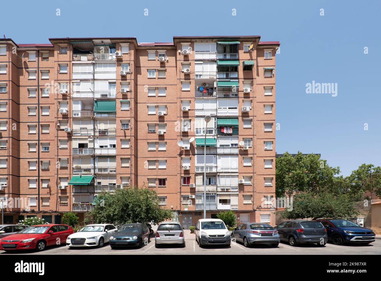 Facades of urban houses with many twin windows and balconies with green awnings Stock Photo