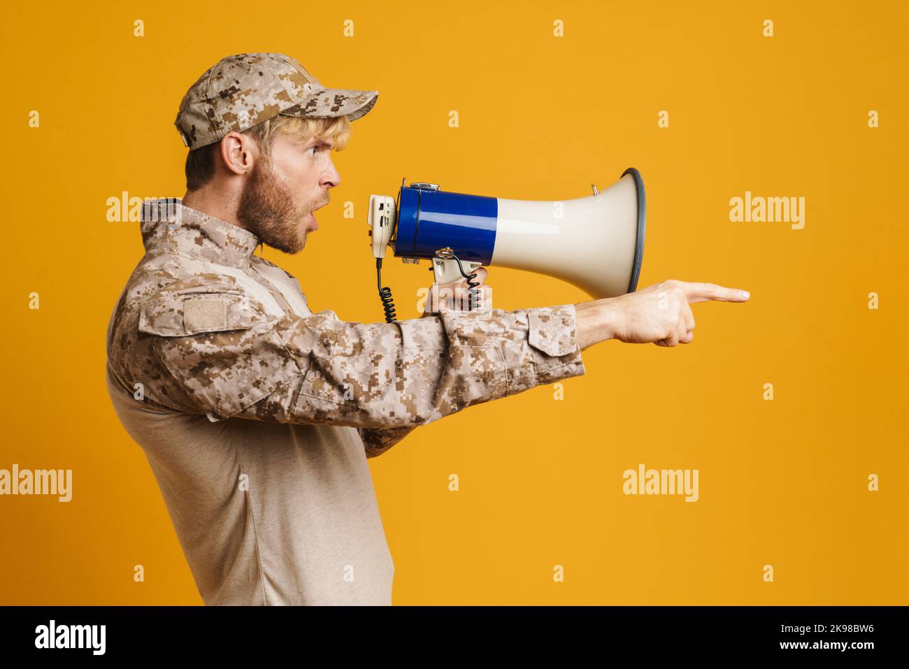 European military man wearing uniform shouting in megaphone isolated over  yellow background Stock Photo - Alamy