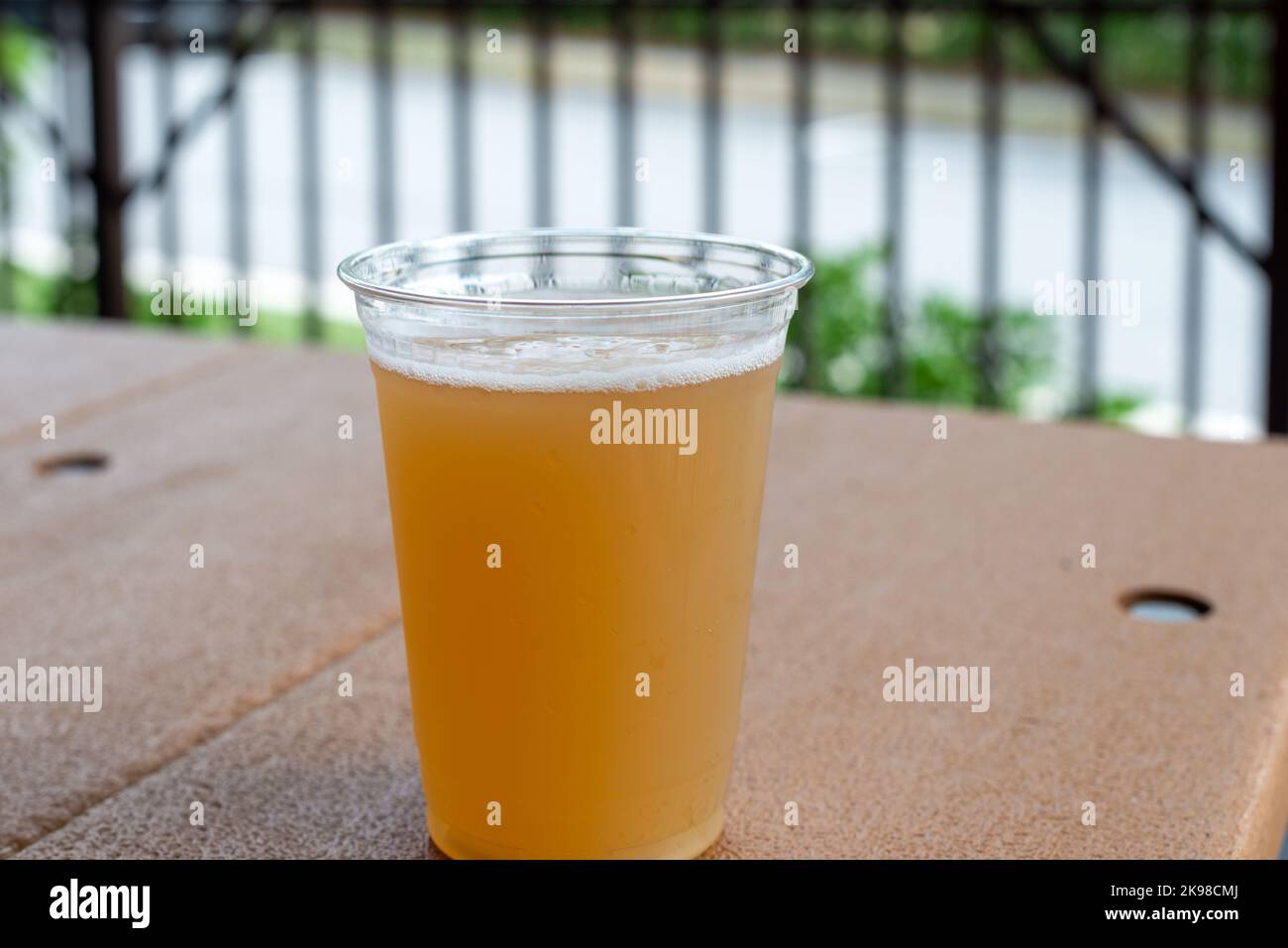 A tall clear plastic glass of sour craft beer in a microbrewery. The