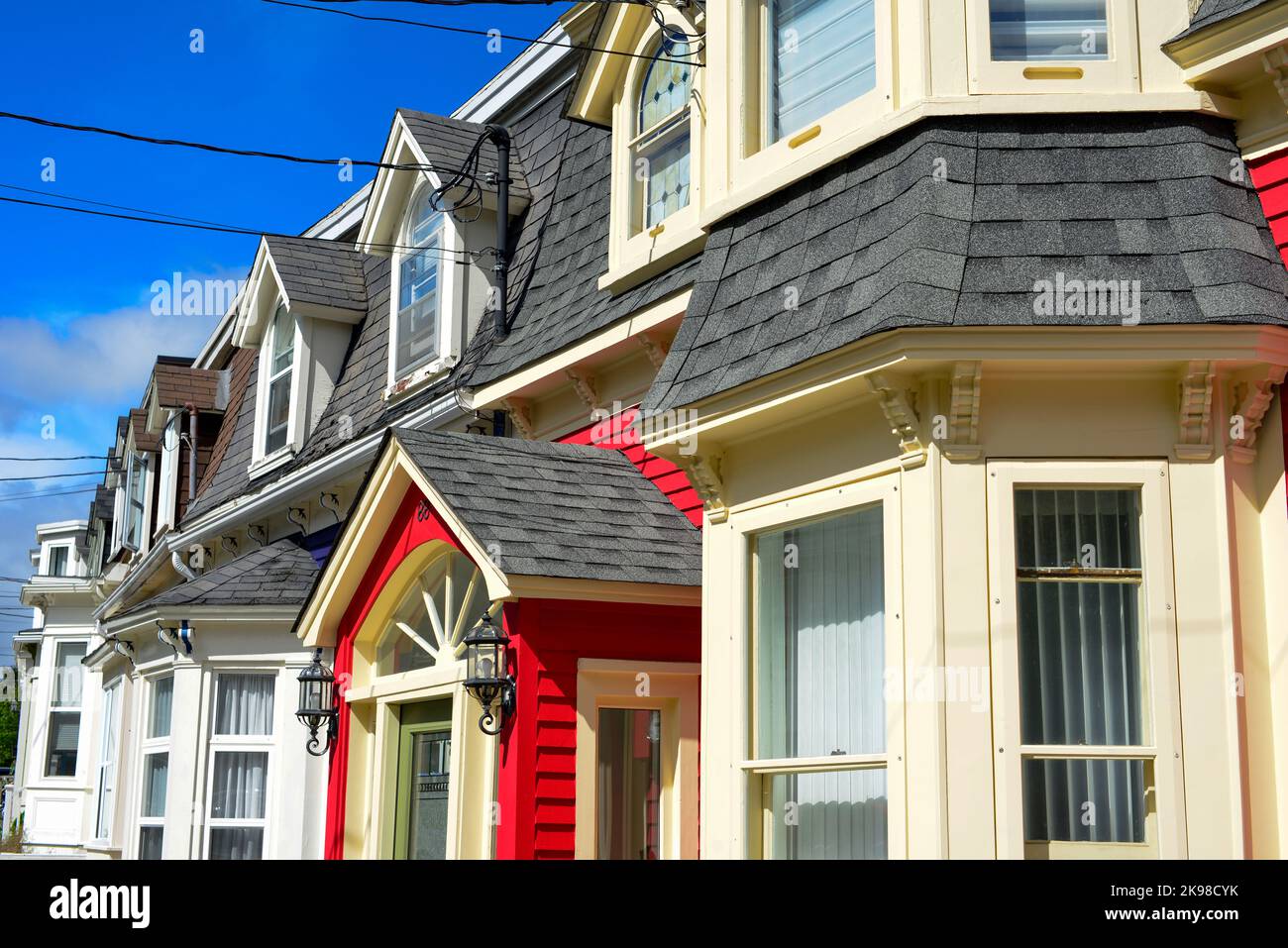 Brightly colored wooden row houses with a blue sky in the background. The three story houses are yellow, red, blue, and green in color with white case Stock Photo