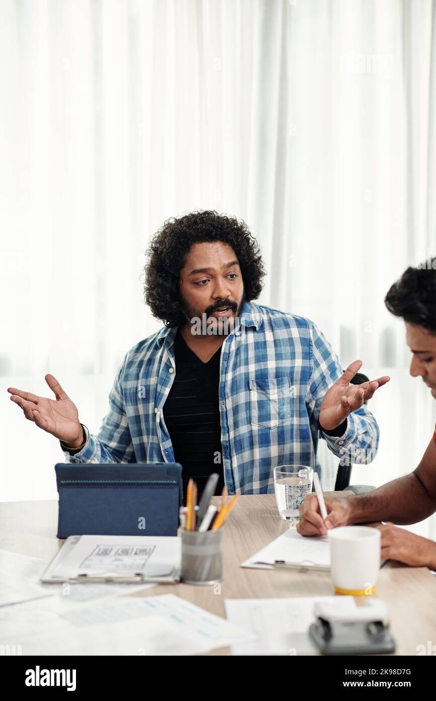 Emotional team leader talking to middle software developer at meeting Stock Photo