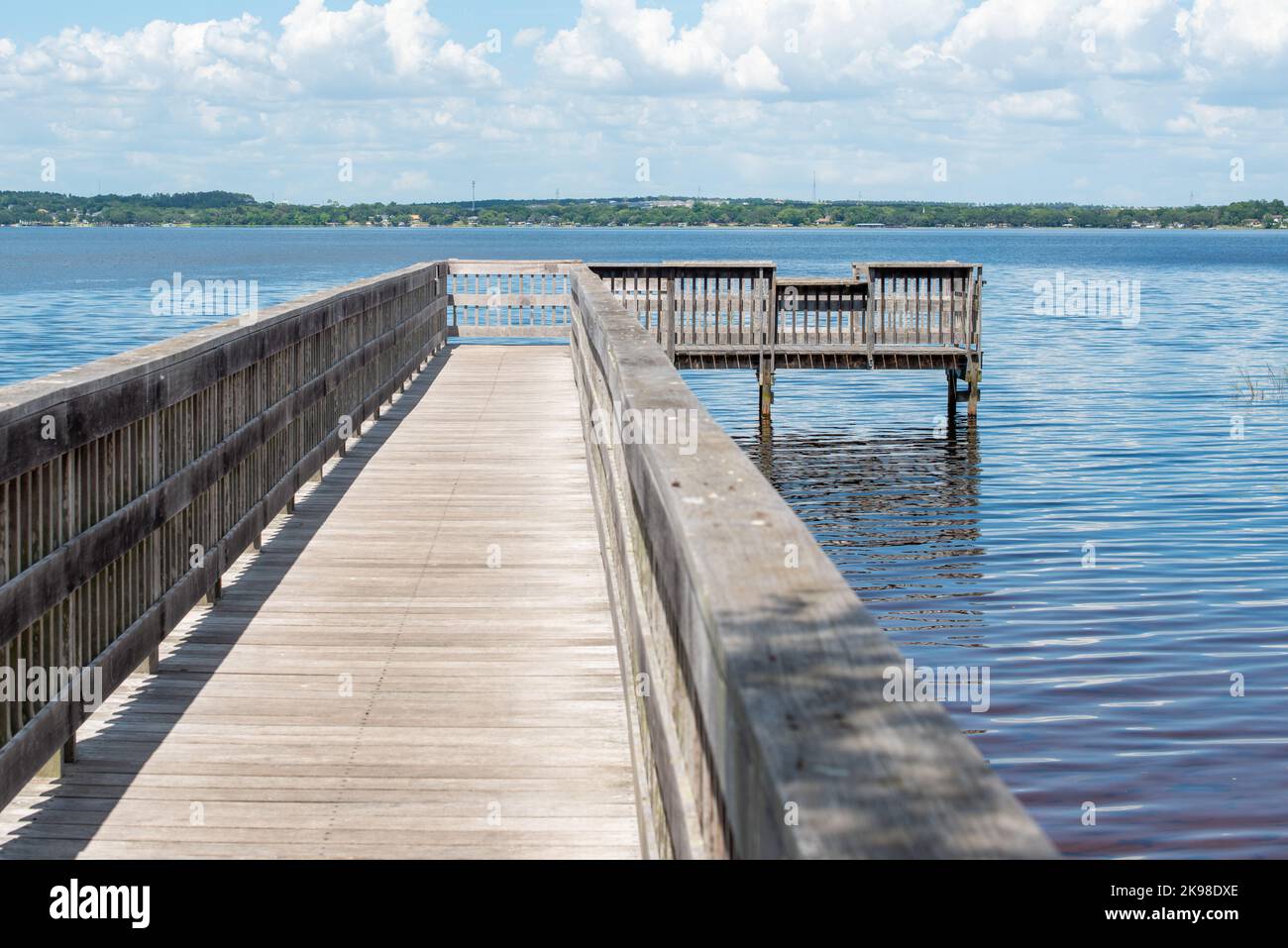 A long wooden finger pier wharf with wood railings stretching out into