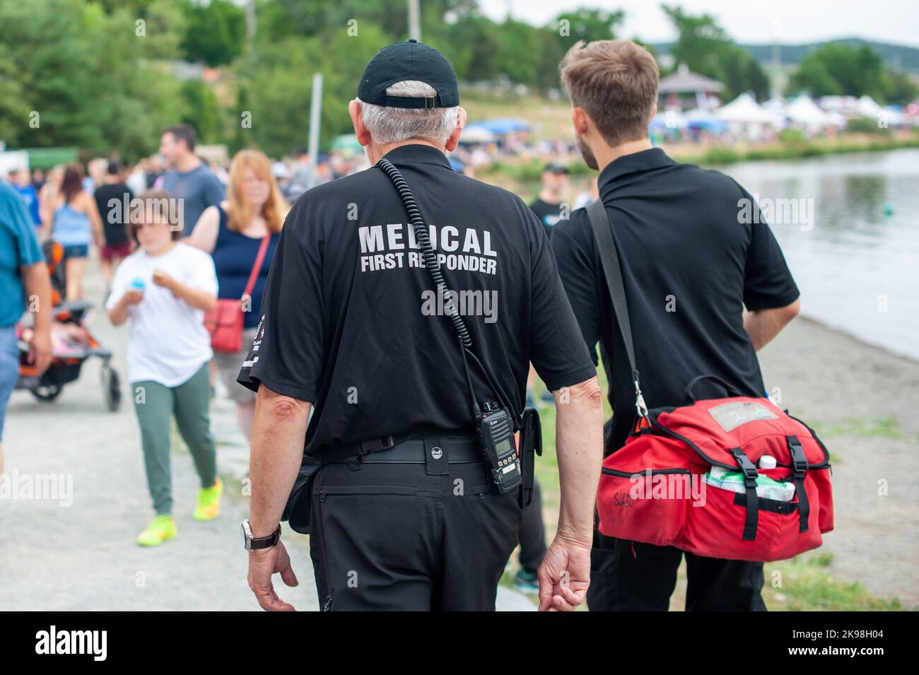 Medical first responders walk along a road wearing black uniforms, with the medical first