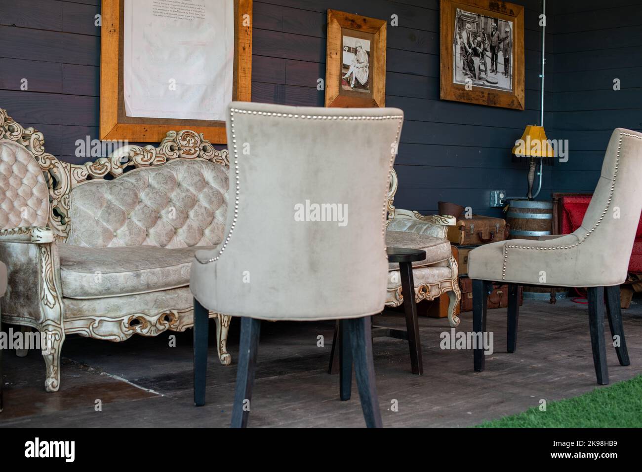 An elegant bone white vintage upholstered chesterfield with a single arm chair. The  furniture has a champagne colored fabric with buttons on the back Stock Photo