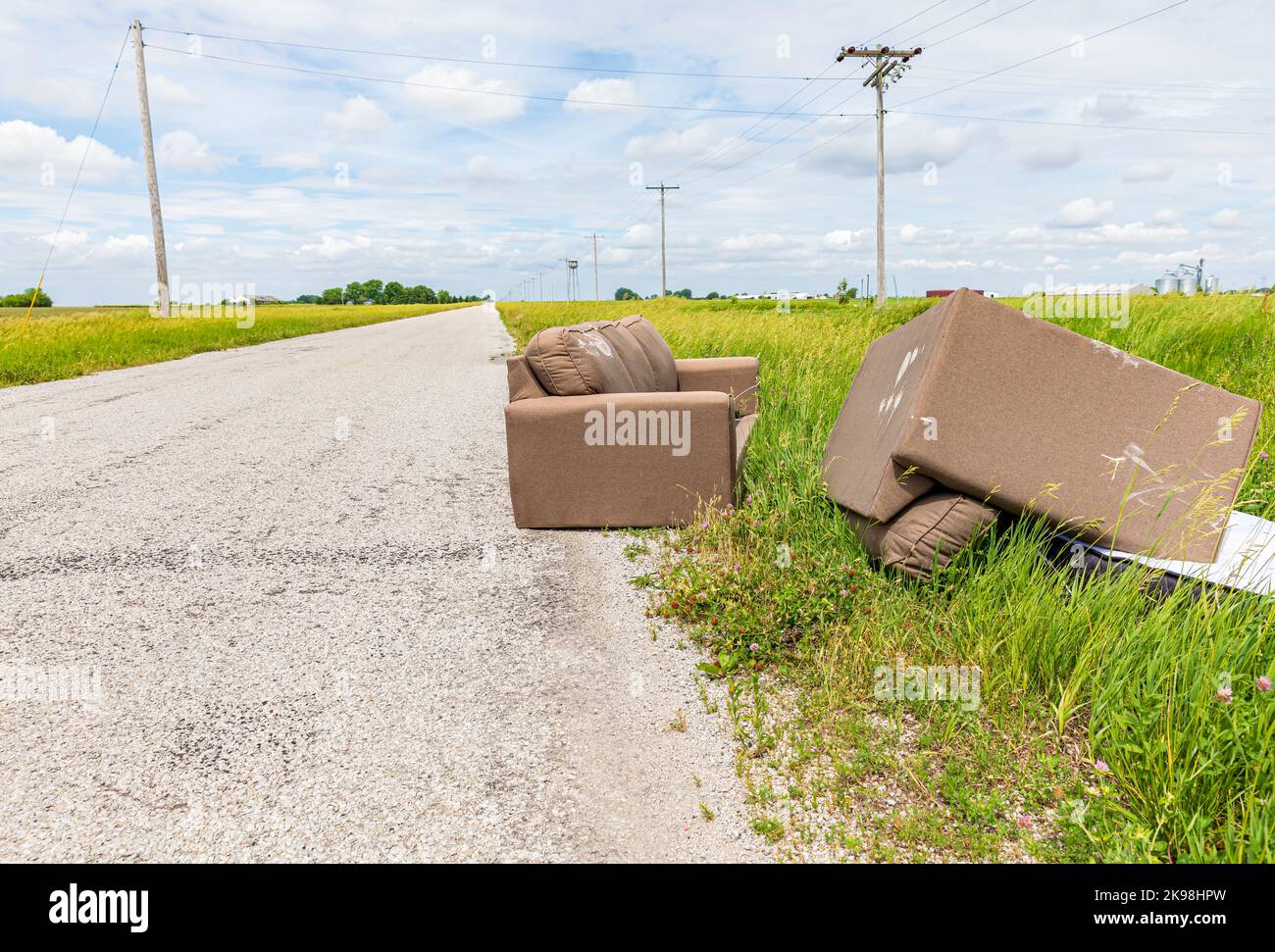 Furniture dumped in ditch of road. Fly dumping, pollution and littering concept Stock Photo