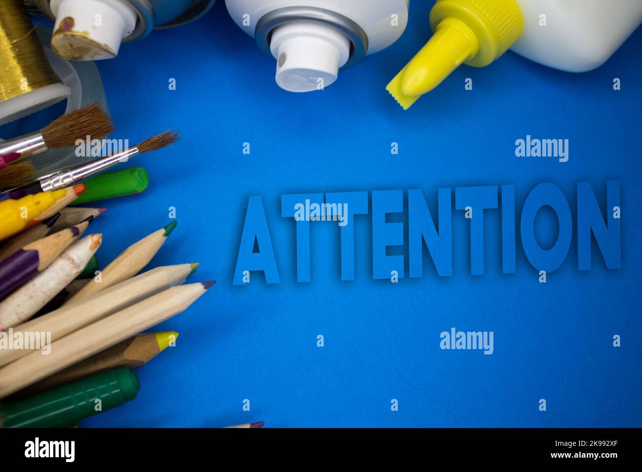 Overhead shot of school supplies with Attention text. Brushes, pencils