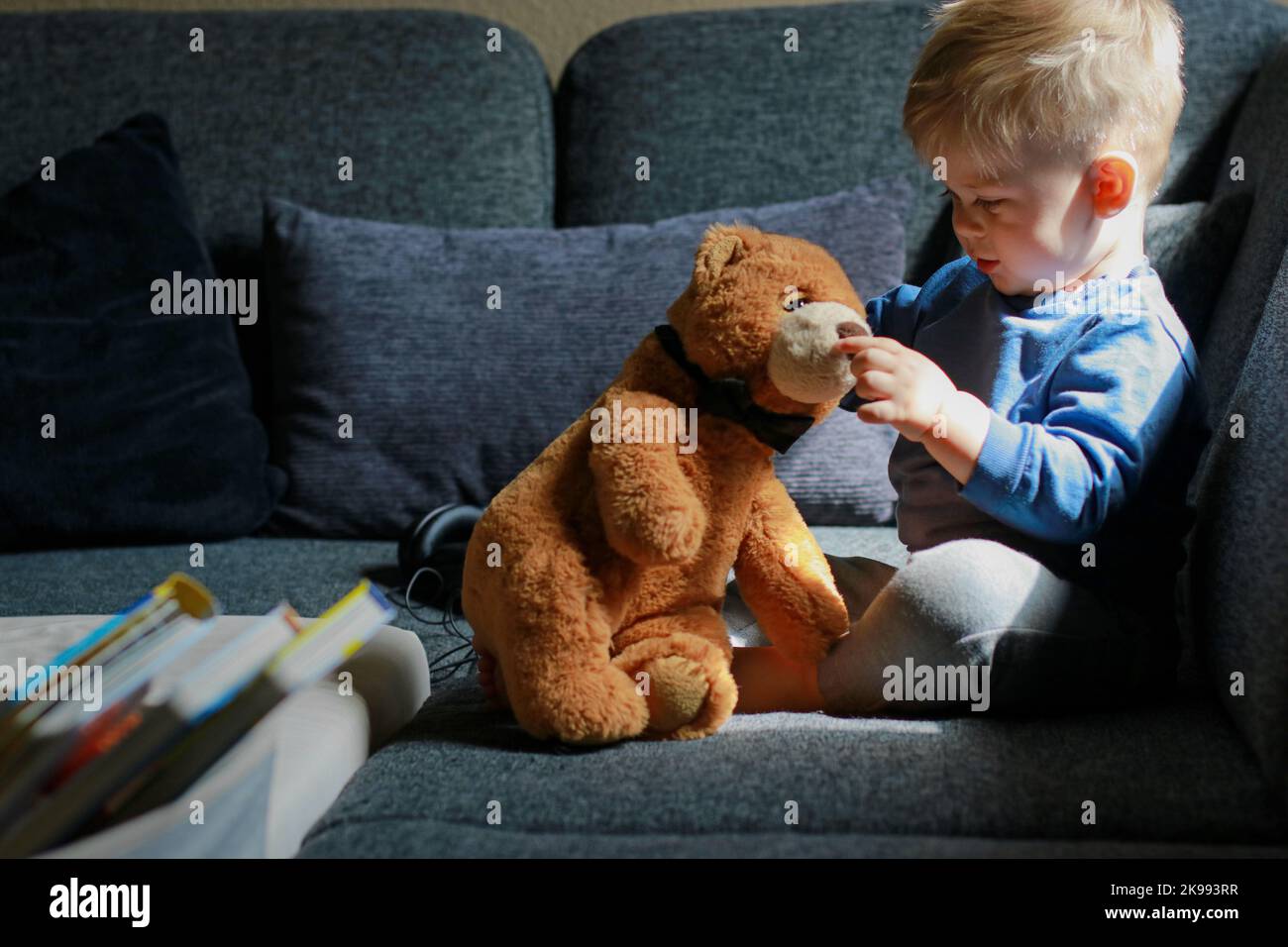 little boy playing on sofa and hugging stuffed teddy bear Stock Photo ...