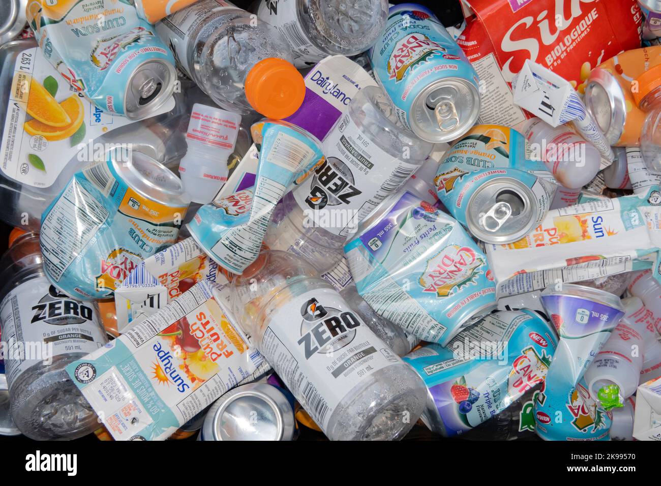 Close up to a several recyclable aluminum cans with clear and coloured plastics with glass