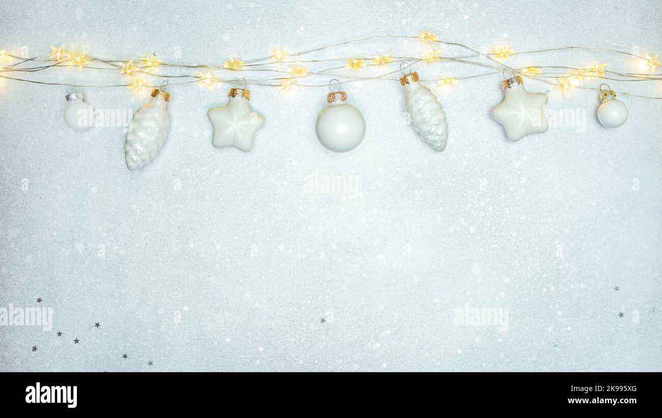 christmas decorations hanging on the rope of garland lights against silver background Stock Photo
