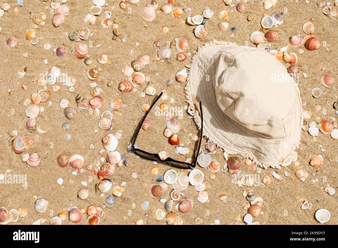Stylish bucket hat with sunglasses and seashells on sand Stock Photo ...