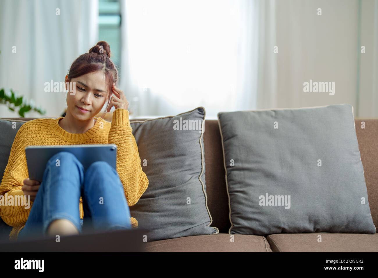 Portrait of a young Asian woman using a tablet on the sofa Stock Photo ...