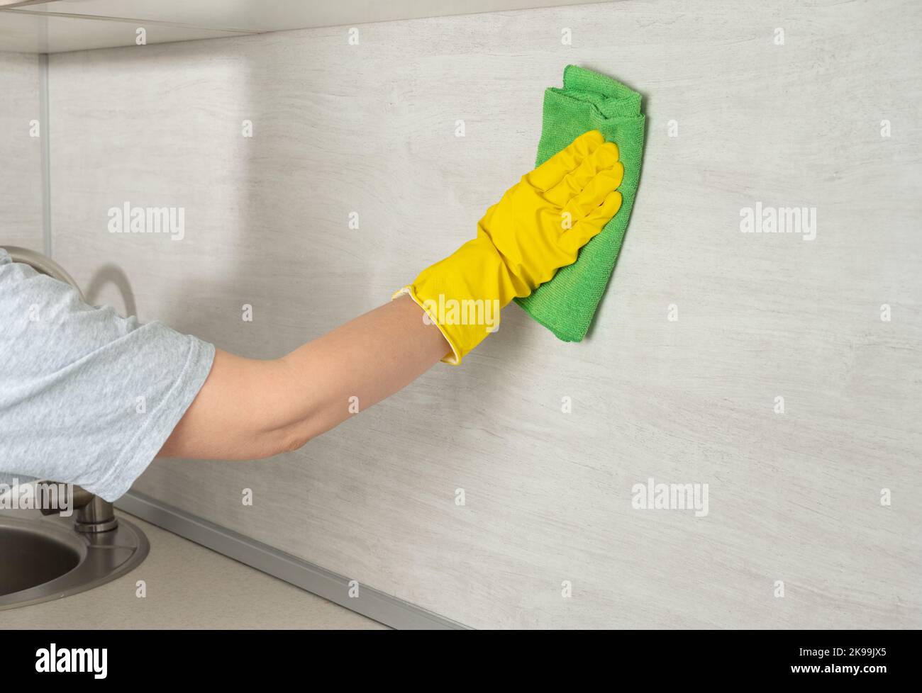 Deep Cleaning service. Cleaning service worker in yellow rubber protective cleaning and polish kitchen surface. cleaning kitchen wall from grease and Stock Photo