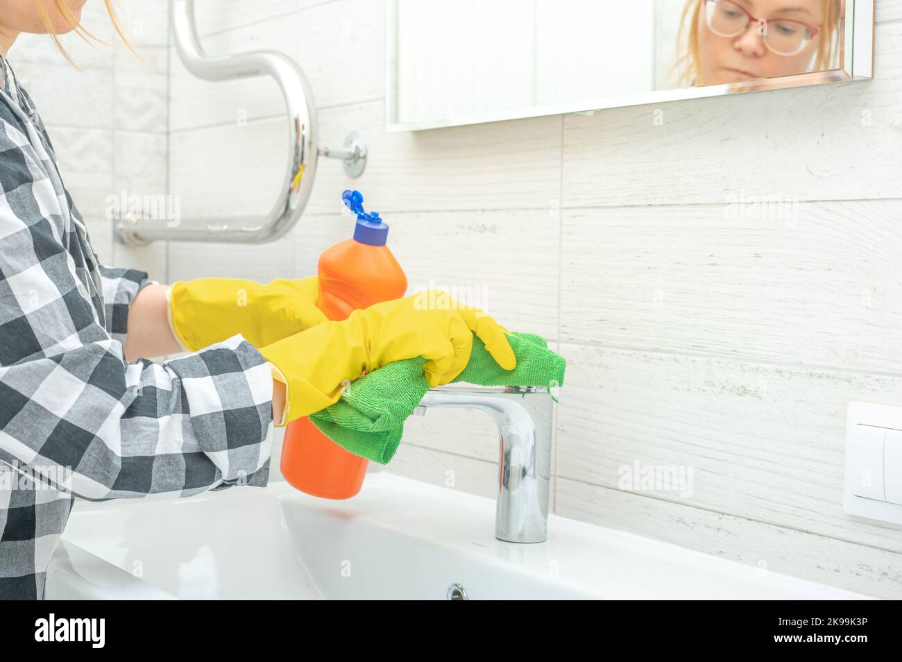 Cleaning service. cleaning tap faucet with detergent in bathroom. Man