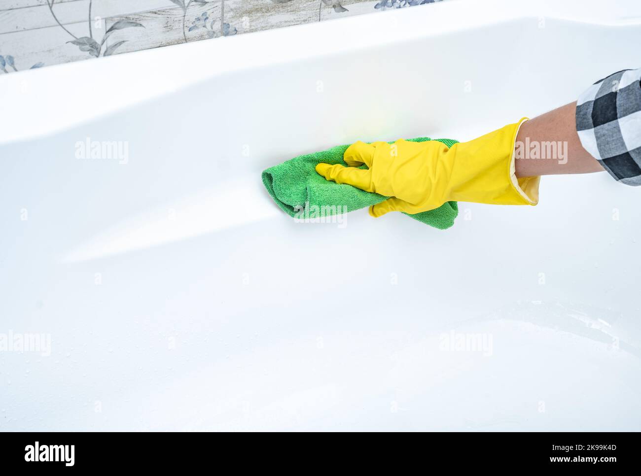 Close up hand cleaning white acrylic bath. Cleaning service. croped