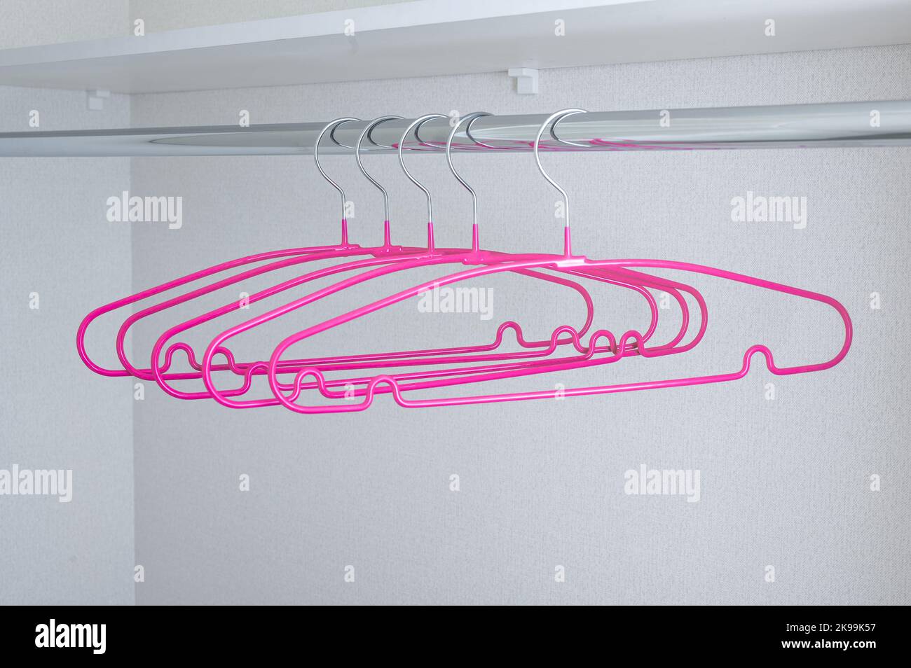 Many pink hangers on rack, grey wall background. Store concept, sale