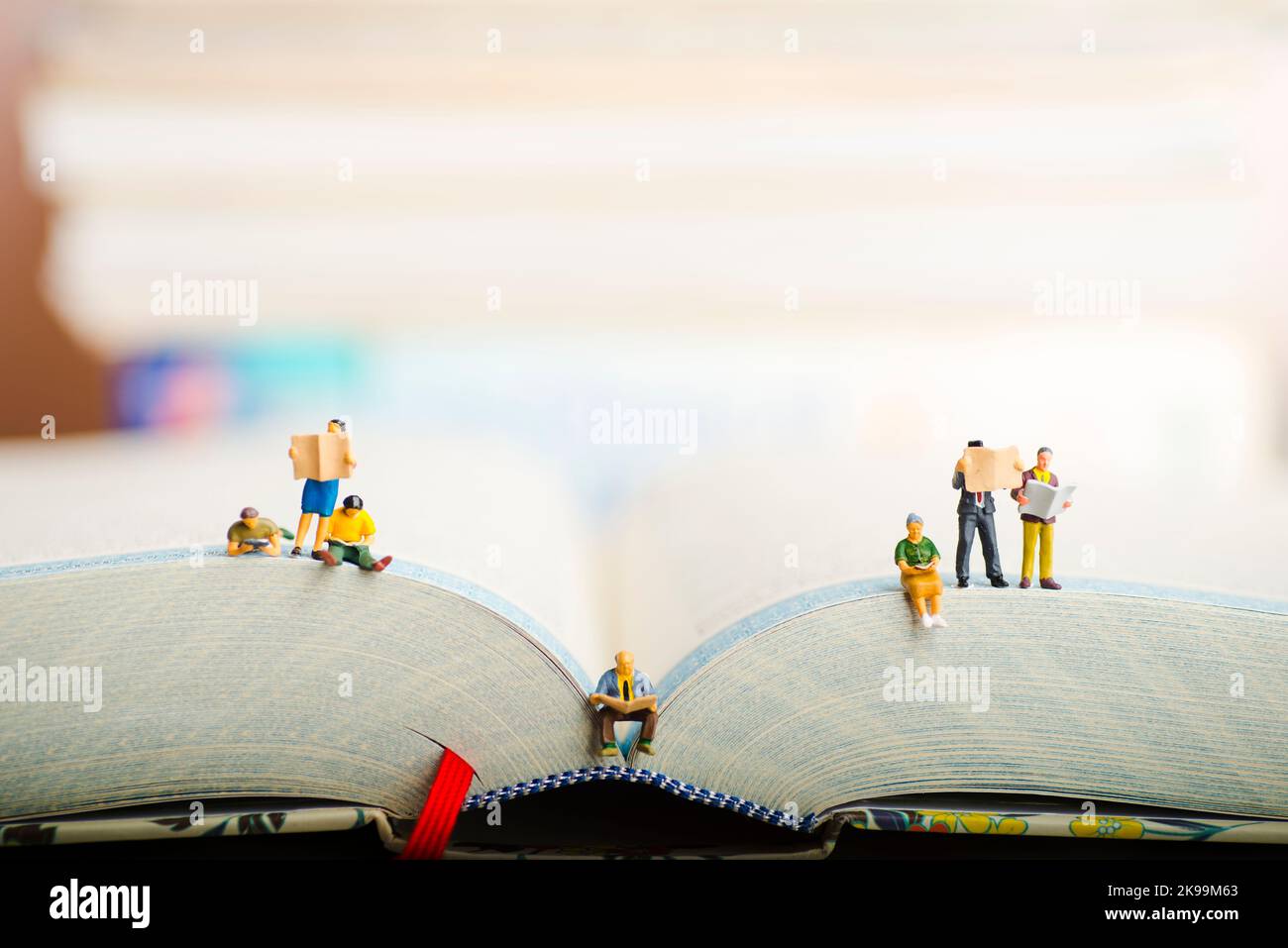 Close up of miniature figures of a group of people read book and newspaper. Stock Photo