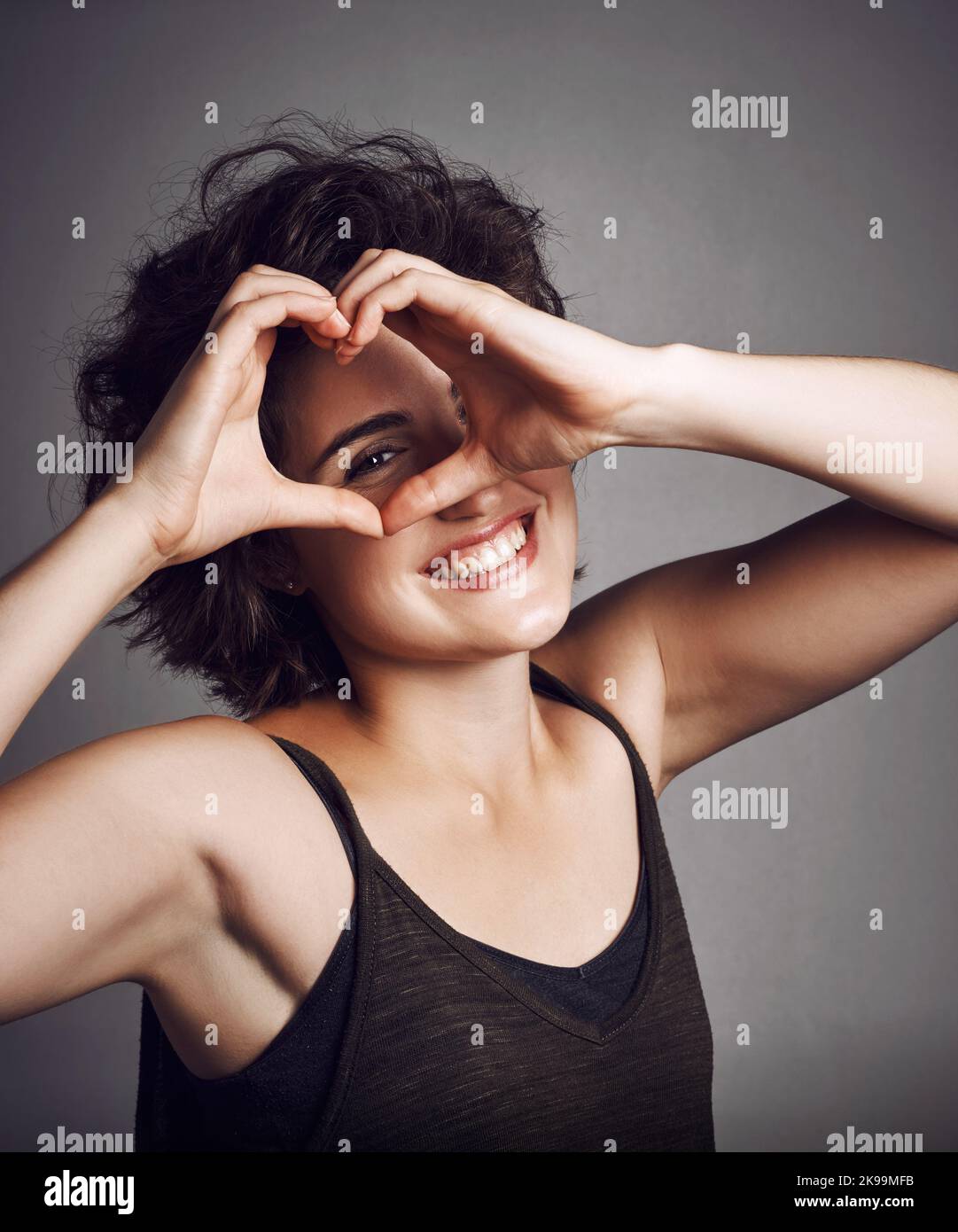 Youll always be in my heart. Studio portrait of an attractive young woman making a heart shape on her eye against a grey background. Stock Photo