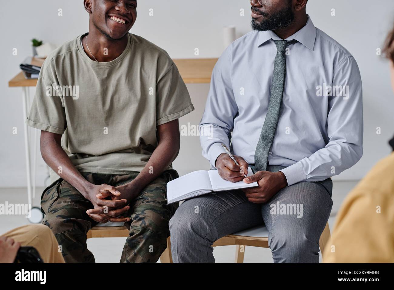 African psychiatrist talking to patient and making notes in notepad at
