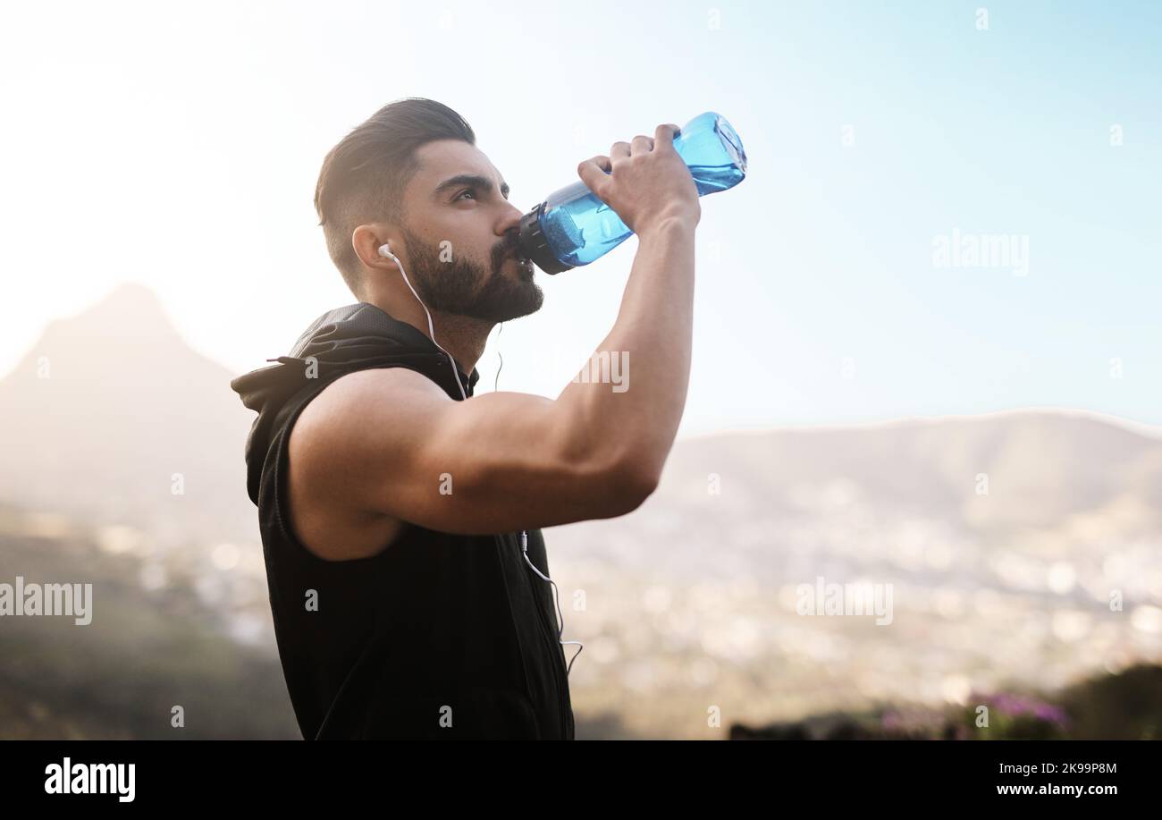 Cooling off after an intense workout. a sporty young man drinking water