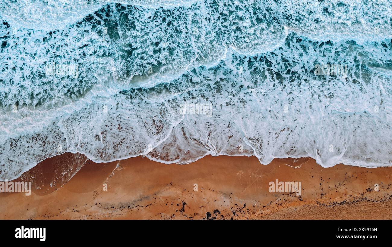 An aerial top view of foamy sea waves splashing on a shore Stock Photo ...