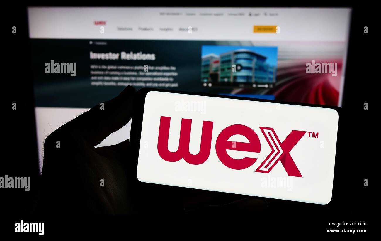 Person holding smartphone with logo of US payment processing company WEX Inc. on screen in front of website. Focus on phone display. Stock Photo