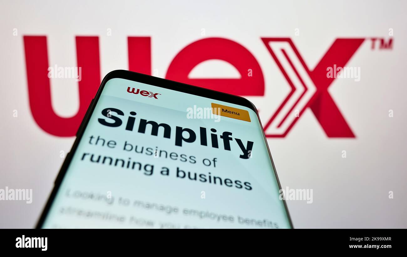 Mobile phone with website of US payment processing company WEX Inc. on screen in front of business logo. Focus on top-left of phone display. Stock Photo