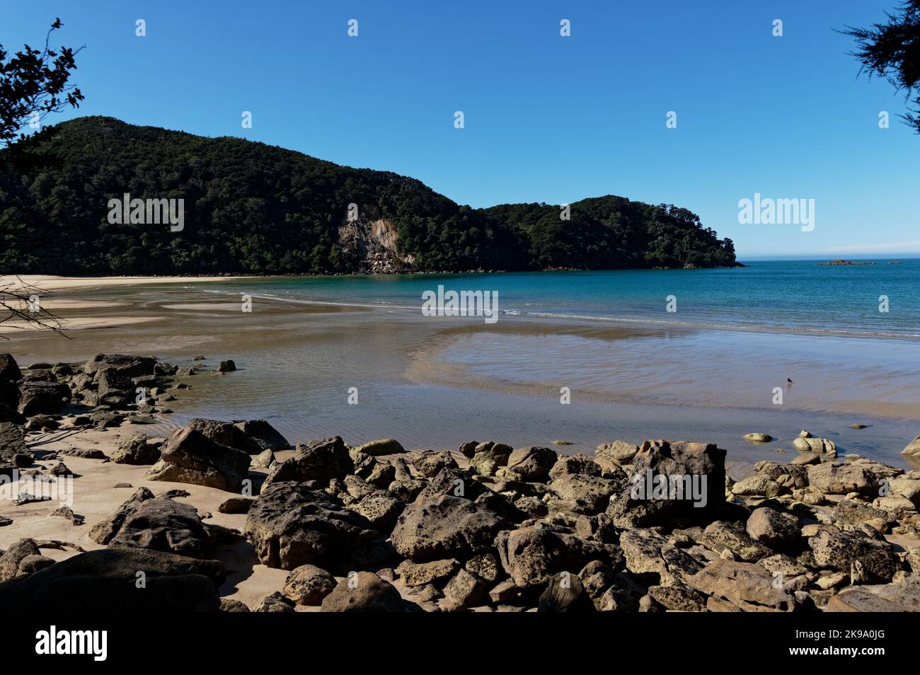 Rocks sit on the foreshore of Bark Bay in New Zealand. Stock Photo