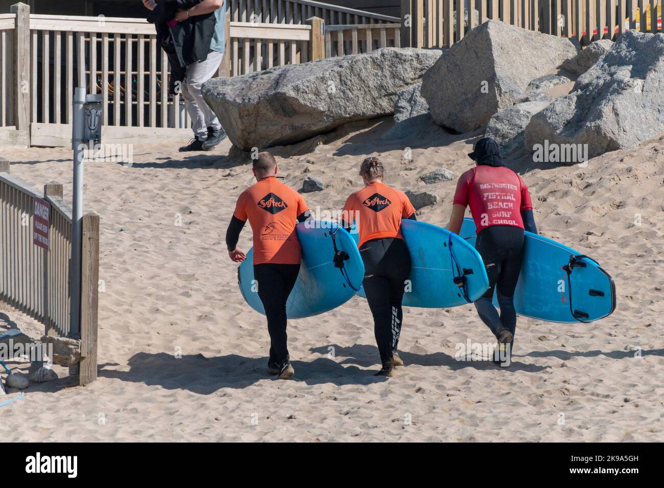 A surfing instructor from the Fistral Surf School and his learners returning after a surfing