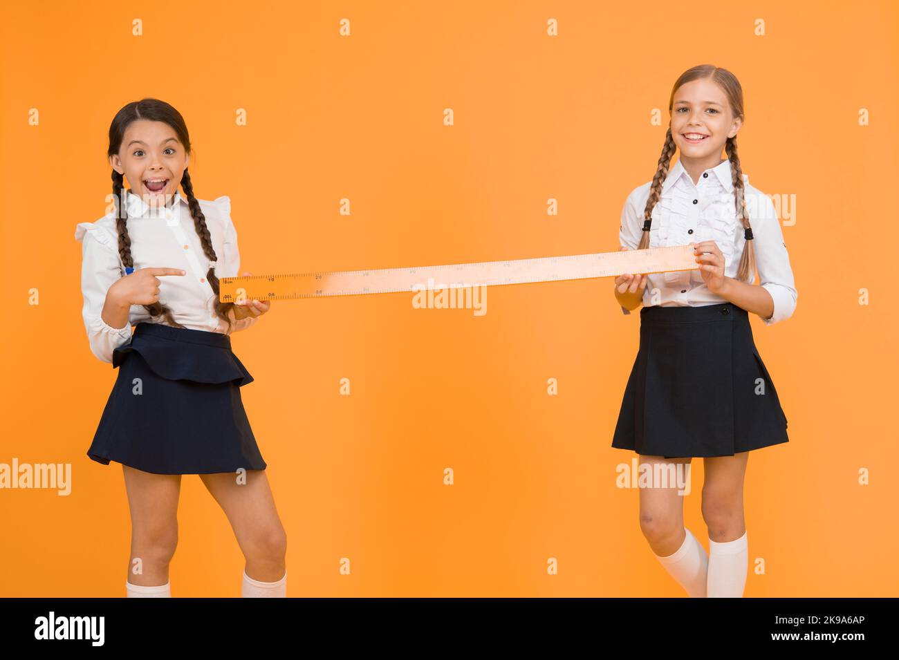 Close or far. Measuring skills. Measuring distance. Measuring equipment. Kids students study math. Knowledge day. Schoolgirls school uniform hold big Stock Photo
