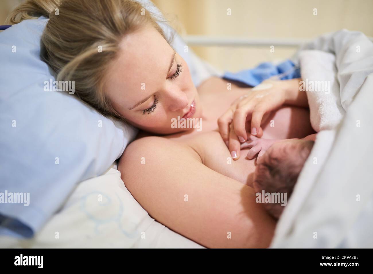 Her tiny little hands will touch so many lives one day. a beautiful young mother lying in bed with her newly born baby girl in the hospital. Stock Photo