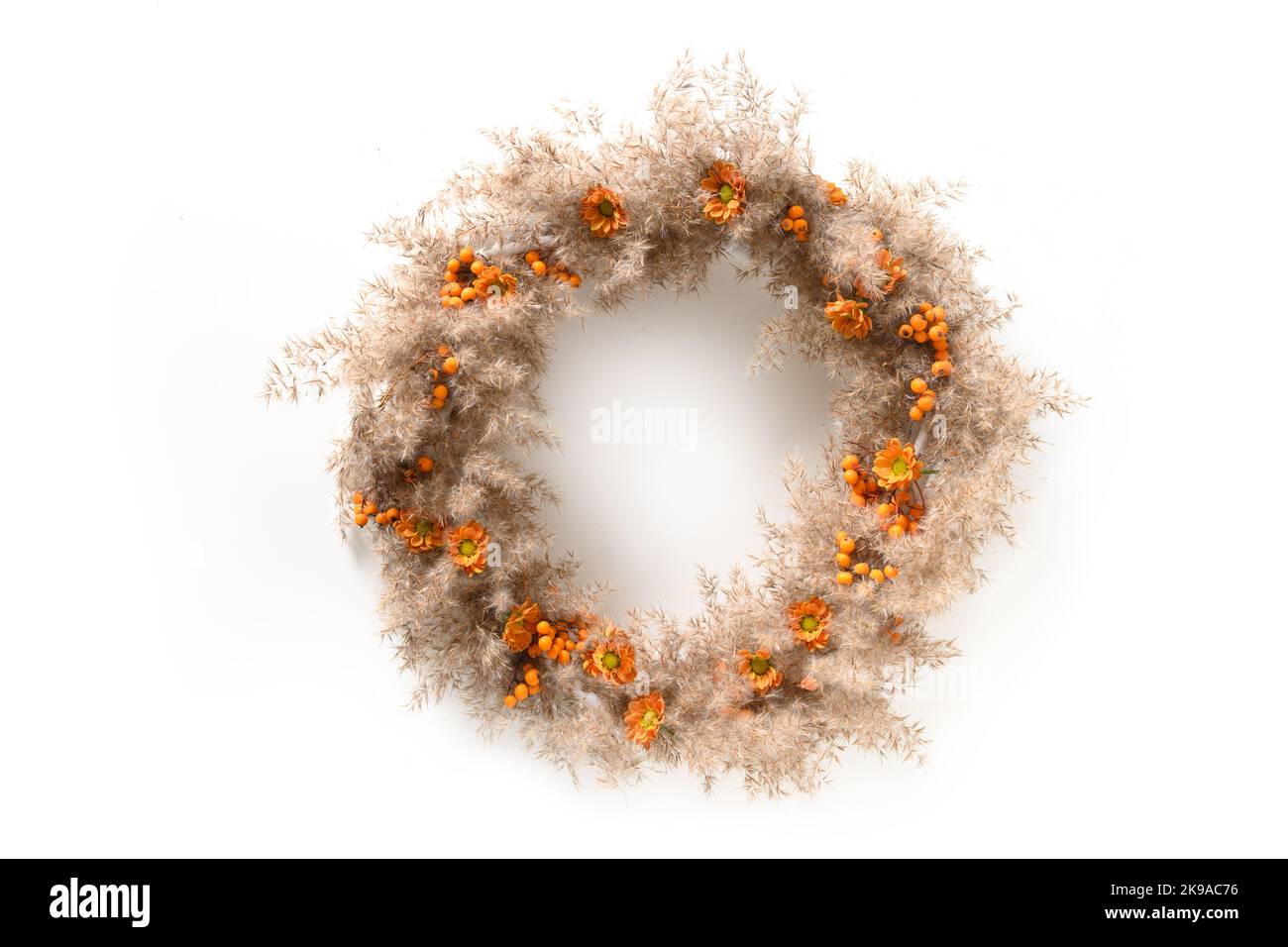 Thanksgiving wreath with orange flowers and dry natural materials isolated over white background. Top view. Stock Photo