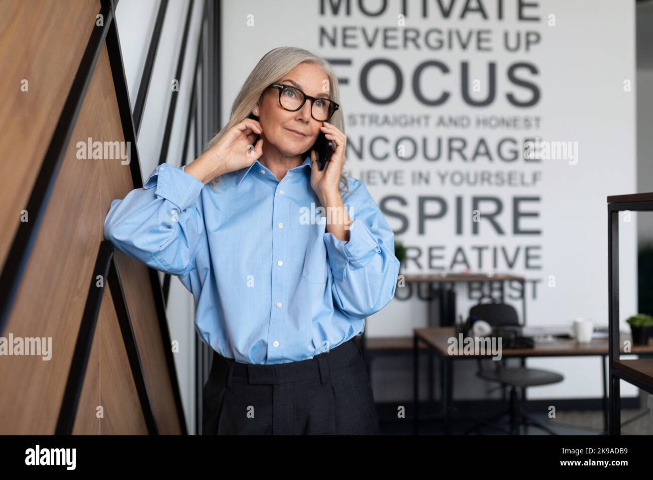 Smiling elegant confident middle aged woman standing in office