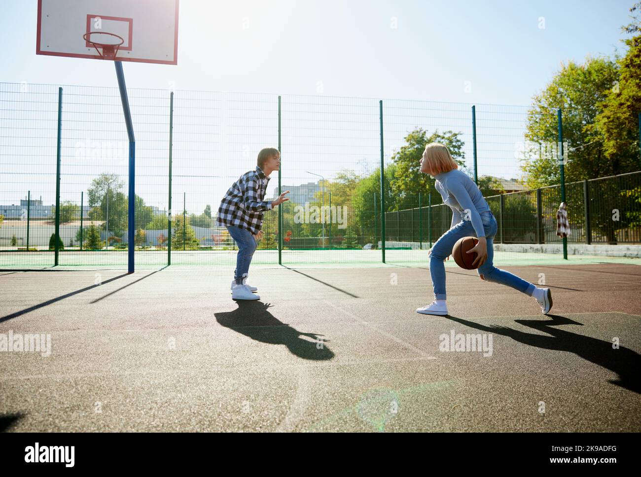 Three teenagers playing streetball with basketball ball at school yard