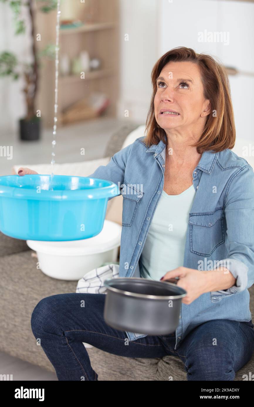 shocked woman collecting water leaking from ceiling Stock Photo Alamy