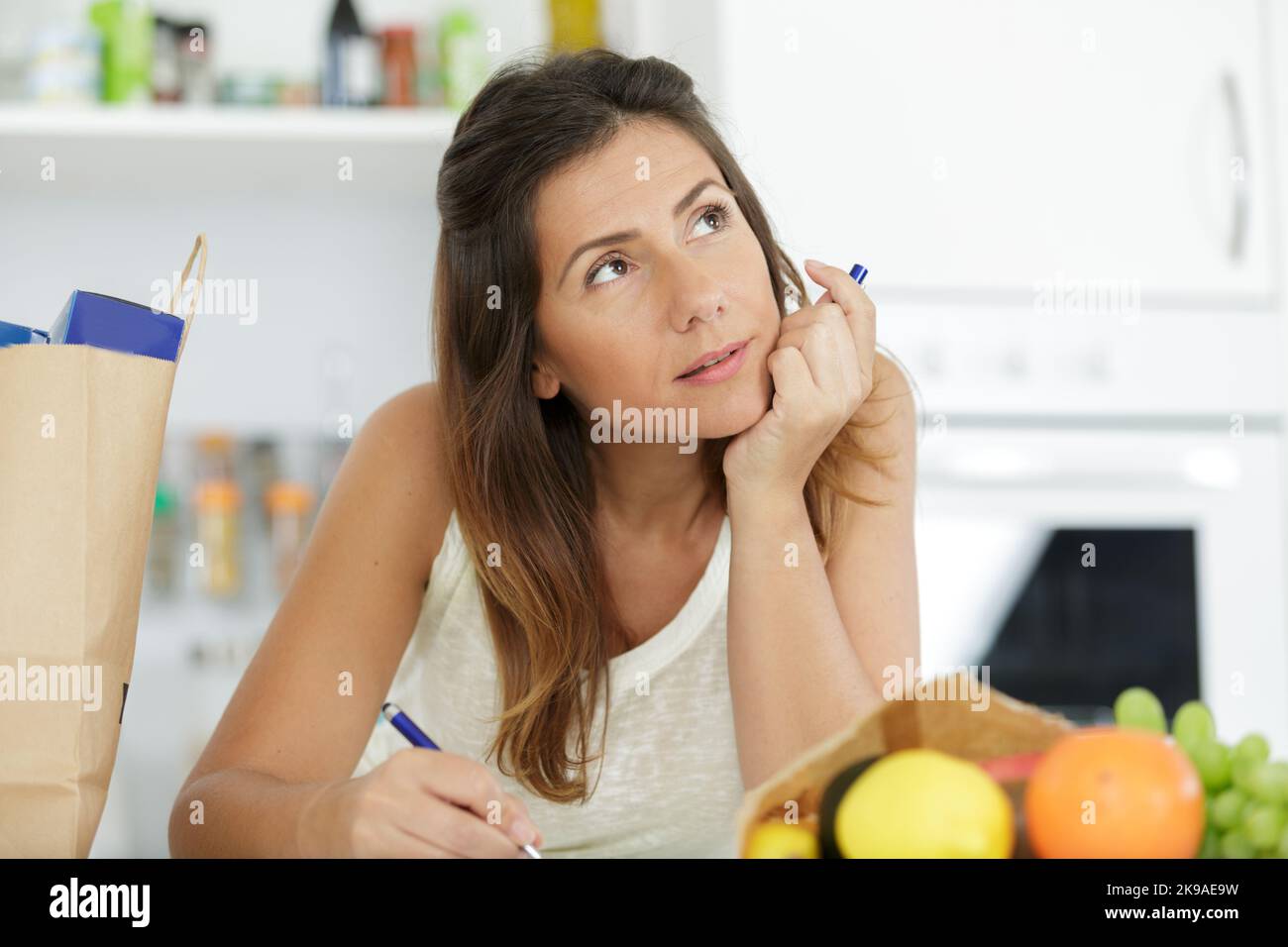 woman writing a list in her kitchen Stock Photo