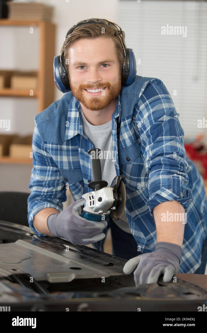 man working with angle grinder to fix car door Stock Photo