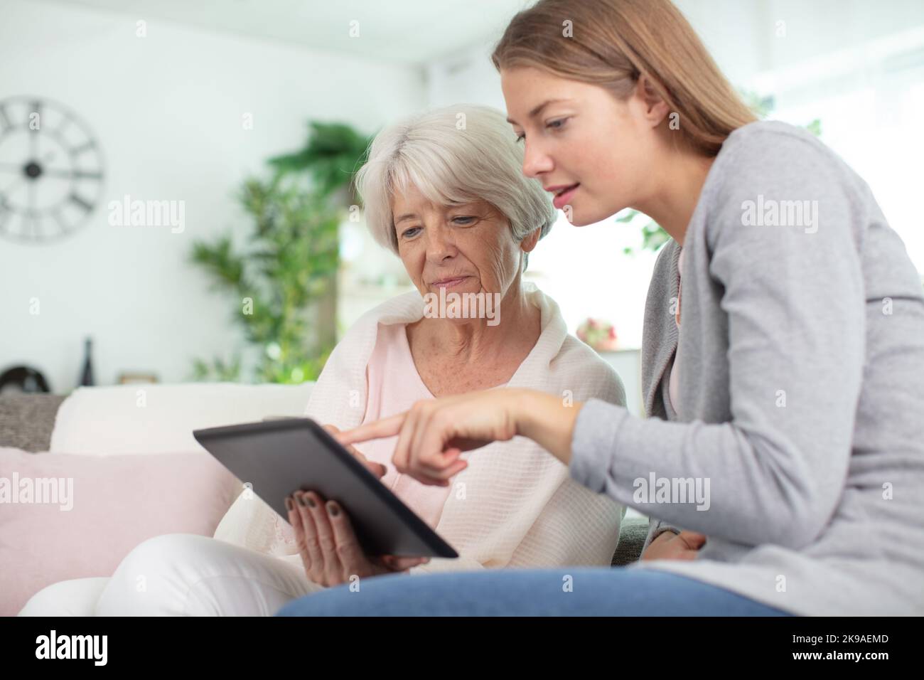 Grandmother learning how to use tablet with granddaughter stock photo
