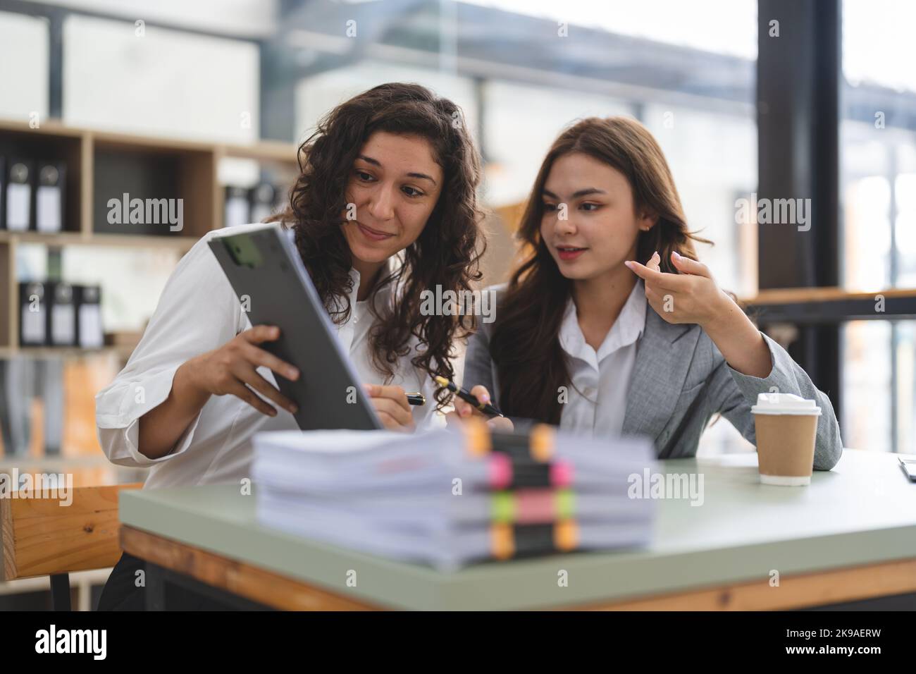 Two smart multiethnic business people working together with laptop while talking about job news in the office. Stock Photo