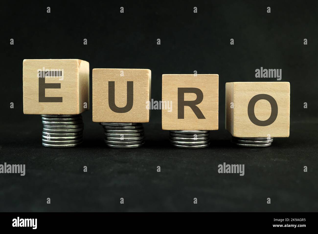 Euro currency weakening, value depreciation and devaluation concept. Decreasing stack of coins on dark black background. Stock Photo