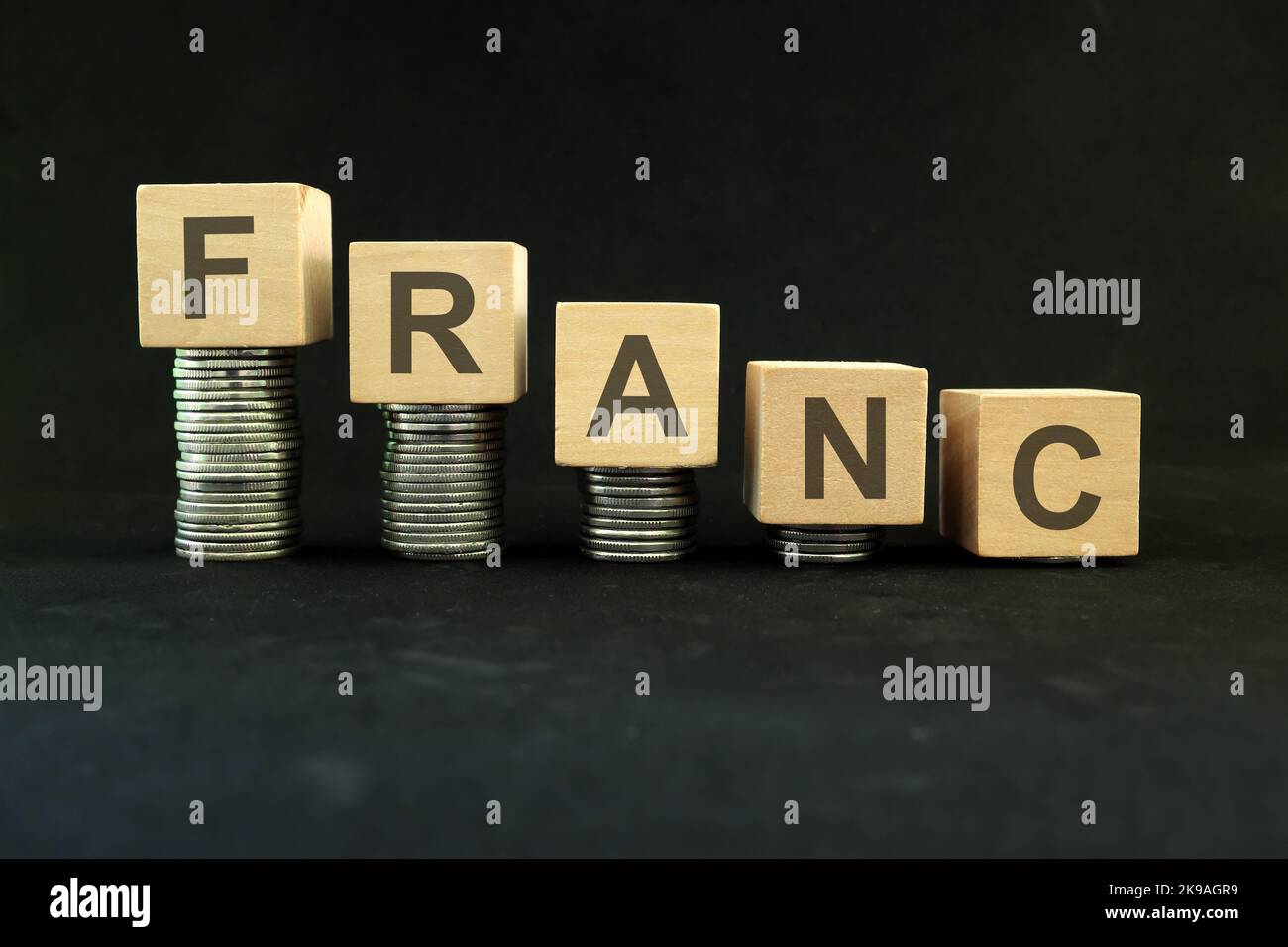 Swiss and French franc currency weakening, value depreciation and devaluation concept. Decreasing stack of coins on dark black background. Stock Photo